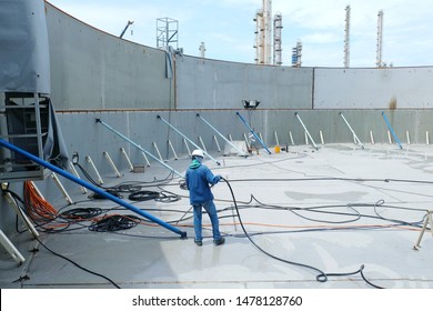 Inside large steel tank that is under constructed   have iron bracing  including workers are using the wind to blow water to clean to store chemicals 