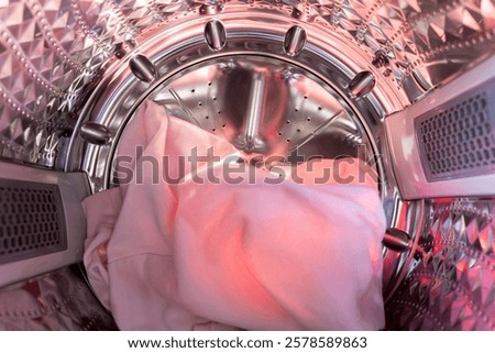 Inside the laundry. A view from inside a washing machine drum, showing colorful clothes, including knits. 
