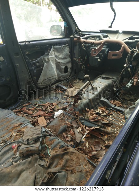 Inside a long abandoned car. Rusty and full of\
dried leaves.