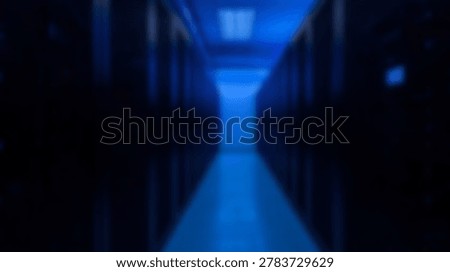 Inside a modern data center, rows of servers are neatly arranged. The server room is well-lit with a blue hue, showcasing advanced technology and data storage.