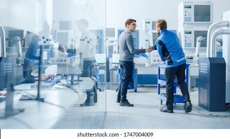 Inside Modern Factory In Facility Workshop Professional Workers Using High-Tech Industrial CNC Machinery, Robot Arm. Professional Industrial Engineer Meets Project Supervisor. Hand Shake.