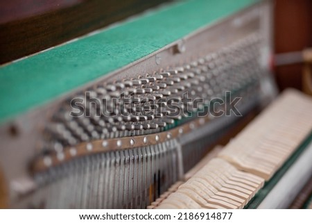 The inside of the piano is without a lid. Strings, hammers and other parts of a musical instrument are visible. Tuning and repair of a musical instrument