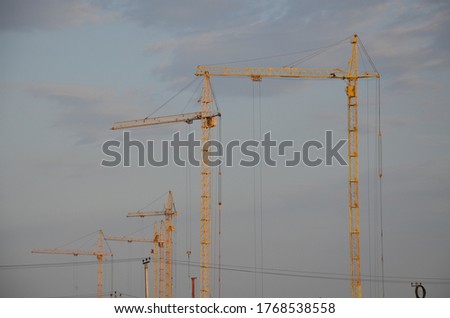 Inside place for many tall buildings under construction and cranes under a blue sky working on place with tall homes.