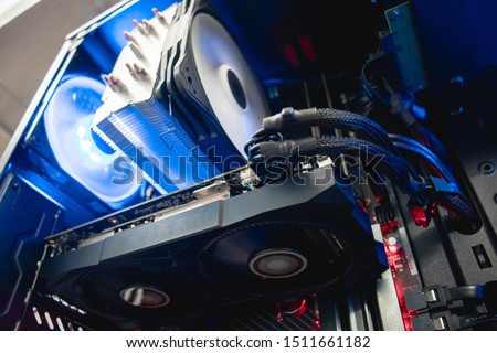 Inside of a professional gaming computer, video graphics card mounted on a motherboard/mainboard, blue shining fan