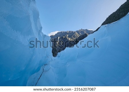 Inside a shallow crevasse of the glacier at fox glacier mountain in New Zealand. The ice wall has a nice light blue hue.