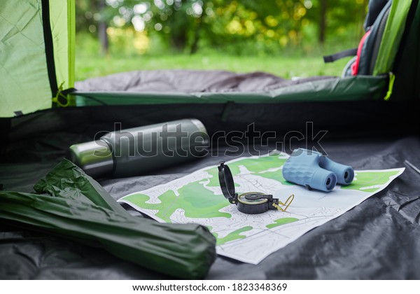 From inside shot of empty tent with camping\
equipment, mcompass and map, copy\
space