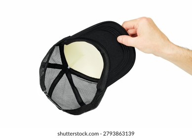 inside side of a black trucker cap with mesh is held by a man hand on an isolated white background, internal lining and size adjuster are visible, demonstration of the reverse side of headwear