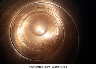 Inside The Spiral Galvanized Large Steel Pipe On With Background Light, The Front And Back Background Is Blurred With A Bokeh Effect. Spiralweld Pipe Is Manufactured From Steel Coil.