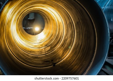 Inside The Spiral Galvanized Large Steel Pipe On With Background Light, The Front And Back Background Is Blurred With A Bokeh Effect. Spiralweld Pipe Is Manufactured From Steel Coil.