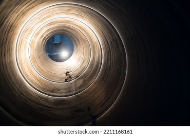 Inside The Spiral Galvanized Large Steel Pipe On With Background Light, The Front And Back Background Is Blurred With A Bokeh Effect. Spiralweld Pipe Is Manufactured From Steel Coil.