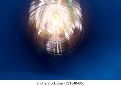 Inside The Spiral Galvanized Large Steel Pipe On With Background Light, The Front And Back Background Is Blurred With A Bokeh Effect. Spiral Weld Pipe Is Manufactured From Steel Coil.