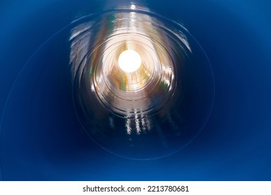 Inside The Spiral Galvanized Large Steel Pipe On With Background Light, The Front And Back Background Is Blurred With A Bokeh Effect. Spiral Weld Pipe Is Manufactured From Steel Coil.