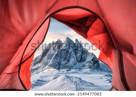 Inside a tent pitching on snow covered hill with majestic mountain on winter at Senja island, Norway