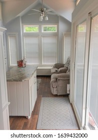 Inside Of A Tiny Home In The Living Area With Combine Kitchen. Wooden Flooring And Kitchen Island In The Middle With Large Windows And Sliding Glass Door.