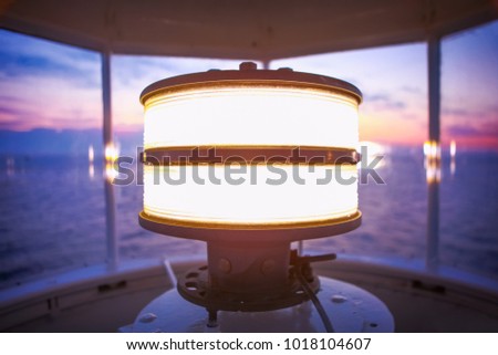 Inside the top of a lighthouse overlooking the sea with the ligh