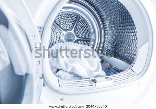 Inside of tumble dryer with clean white\
towels - new generation of dryer,  household\
concept