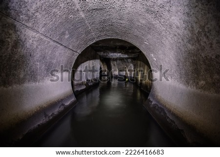 Inside underground urban sewer system. Sewage flowing in round sewer pipe.