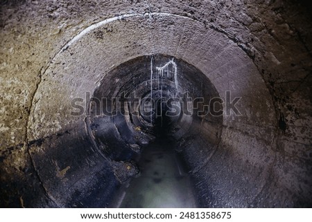 Inside underground urban sewer system. Sewage flowing in round sewer pipe.