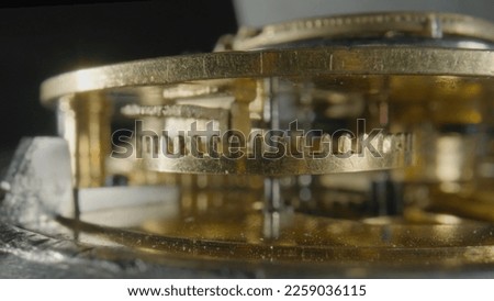 Inside view of a clockwork of golden mechanical clock on black isolated studio background. Gold gears, gearing, wheel with toothed. Disassembled watch with cogwheel and spring. Macro shot .