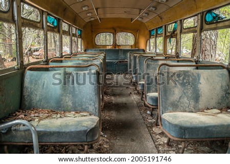 Inside view closeup of a abandoned old vintage school bus with seats and broken windows and a rotting interior exposed to the outdoor elements