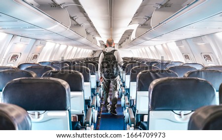 Inside view of commercial airplane with lonely man traveler - Emergency travel concept about flight delays and cancellations - Aerospace industry crisis with empty plane on bright azure filter