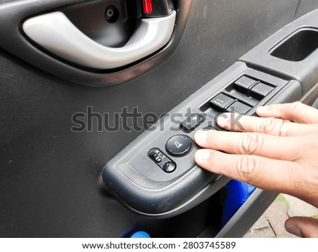 Inside view of a driver operating the central lock and window control console on a car panel