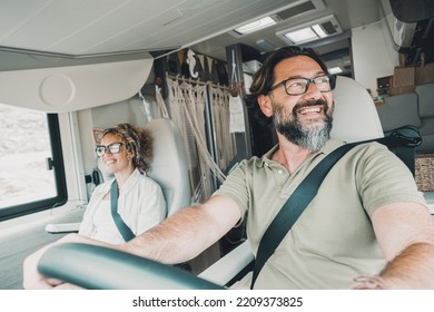 Inside view of happy adult couple driving and enjoying road trip in a modern camper van vehicle. Concept of alternative home and lifestyle. People living off grid in motor home and travel vacation - Powered by Shutterstock