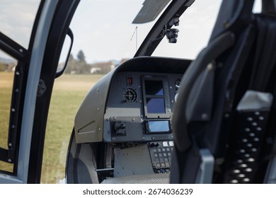 Inside view of a helicopter cockpit with controls and screens set for an upcoming flight over an open field.