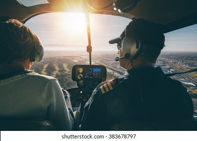 Inside view of a helicopter in flight, with man and woman pilots flying a helicopter on a sunny day.