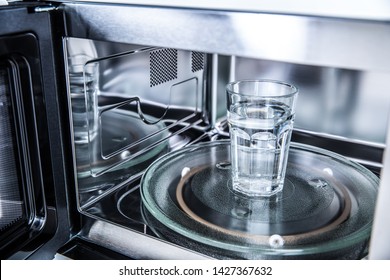 Inside View Of New Clean Staniless, Microwave Oven With A Cup Of Pure Water.