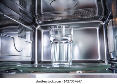 Inside View Of New Clean Staniless, Microwave Oven With A Cup Of Pure Water.