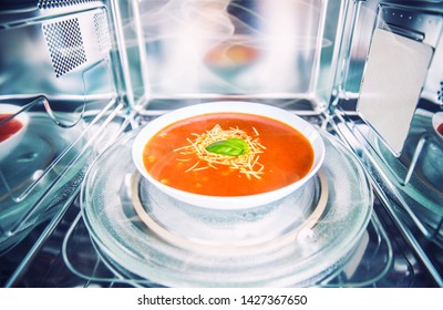 Inside View Of New Clean Staniless Microwave Oven With A Tomato Soup In White Plate.