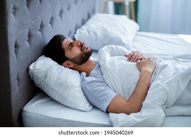 Insomnia. Depressed Arab Man Unable To Sleep, Lying In Bed, Looking Up And Contemplating, Copy Space. Sleeplessness, Mental Health Problem, Male Depression Concept.