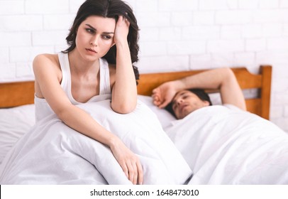 Insomnia Problem. Millennial Woman Can't Sleep, Sitting In Bed Near Sleeping Boyfriend, Free Space