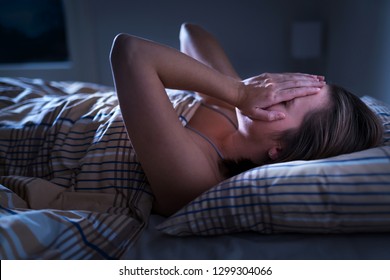 Insomnia, Sleep Apnea Or Stress Concept. Sleepless Woman Awake And Covering Face In The Middle Of The Night. Lady Can't Sleep. Nightmares Or Depression. Suffering From Headache Or Migraine. 