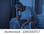 Insomnia, sleeping disorder concept. Sleepless unhappy grey-haired middle aged man wearing pajamas sitting on bed at home, touching his head, cant sleep at night, copy space