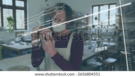 Inspecting masked artisan evaluating ceramic vessel in pottery studio, with digital data overlay. Craftsmanship, creativity, artisanal, workshop, handcraft, design, sculpture