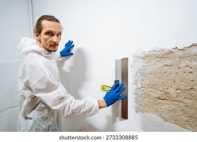 Inspecting Surface And Wall Condition. Worker Examines Wall Surface Before Painting Begins. Worker Carefully Evaluates Wall Surface Condition Prior To Applying Paint With Appropriate Safety Gear
