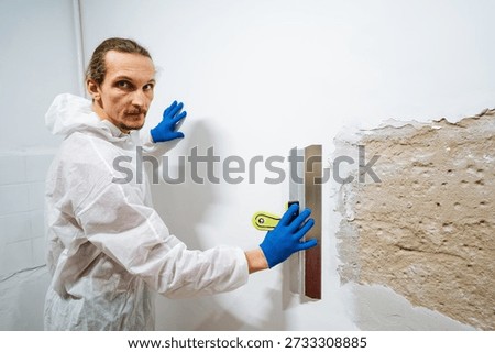 Inspecting Surface And Wall Condition. Worker Examines Wall Surface Before Painting Begins. Worker Carefully Evaluates Wall Surface Condition Prior To Applying Paint With Appropriate Safety Gear