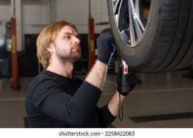 Inspection by a professional car mechanic of tire wear on a car - Shutterstock ID 2258422083