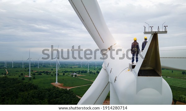 \
Inspection engineers standing on top of a wind\
turbine for Background\
Image.