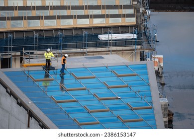 Inspector controlling new window of a light well on the roof of a commercial building.