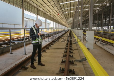 Inspector (Engineer) checking drawing of railway or track in depot of skytrain 