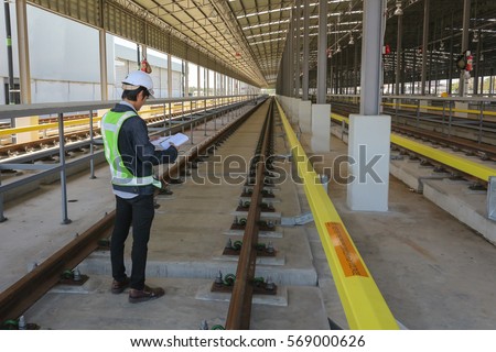 Inspector (Engineer) checking drawing of railway or track in depot of skytrain 