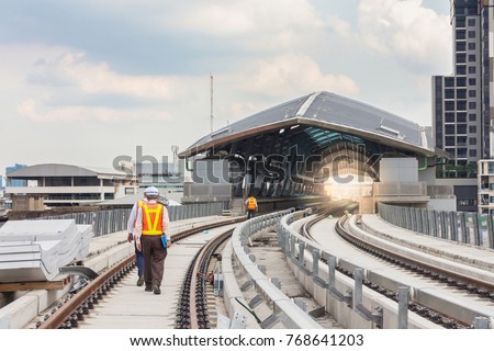 Inspector (Engineer) checking railway construction work on skytrain viaduct. Which railway consist of rail track and conductor rail or third rail.