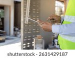 inspector or engineer is inspecting construction and quality assurance new house using a tablet. Engineers or architects or contactor work to build the house before handing it over to the homeowner