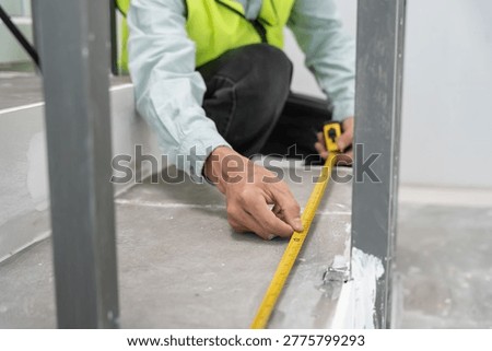 inspector or engineer is inspecting construction and quality assurance check dimension of house by using a tape measurement. Engineers or architects or contactor work to build the house before sell.