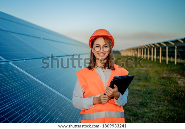 Inspector Engineer Woman Holding Digital Tablet\
Working in Solar Panels Power Farm, Photovoltaic Cell Park, Green\
Energy Concept.