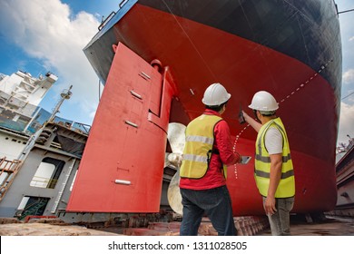 inspector, port controller, surveyor, foreman inspecting the final repairing of painting cleaning over hull dry dock of the commercial ocean ship, checking detail and report on line the progress works