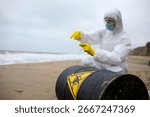 An inspector in a protective suit takes samples into a test tube next to toxic waste from a barrel on the beach.